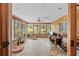 Bright sunroom with stone floors, wood-paneled walls, and large windows showcasing the outdoor landscape at 10193 Wallien Dr, Brooksville, FL 34601