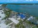 Aerial view of a home near the water with boat lift and beach, surrounded by lush greenery at 1114 Mandalay Pt, Clearwater Beach, FL 33767