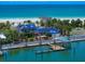 Beautiful waterfront property featuring a blue-roofed home, private boat dock, and direct access to a pristine sandy beach at 1114 Mandalay Pt, Clearwater Beach, FL 33767