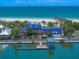 Stunning beachfront home with a blue tile roof, private dock, and lush landscaping, offering direct access to the ocean at 1114 Mandalay Pt, Clearwater Beach, FL 33767