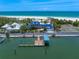 Gorgeous beachfront home with a blue tile roof, private dock, and lush landscaping, steps away from the sandy beach at 1114 Mandalay Pt, Clearwater Beach, FL 33767