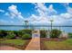 Scenic backyard view with a brick pathway leading to a private dock on the water, surrounded by lush greenery at 1114 Mandalay Pt, Clearwater Beach, FL 33767