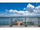 Private dock with boat lift and tranquil blue water views under a bright, partly cloudy sky at 1114 Mandalay Pt, Clearwater Beach, FL 33767