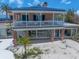 Exterior elevation featuring a blue roof, columns, and a second-story balcony at 1114 Mandalay Pt, Clearwater Beach, FL 33767