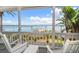 Relaxing porch view with white chairs overlooking the waterfront, featuring a private dock and lush tropical foliage at 1114 Mandalay Pt, Clearwater Beach, FL 33767