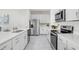 Modern kitchen with stainless steel appliances, white cabinets, and ample counter space with gray flooring at 11739 Blackbrook Ct, Seffner, FL 33584