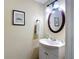 Traditional bathroom with a white vanity, an oval mirror, towel, and framed picture above the toilet at 12464 Berkeley Square Dr, Tampa, FL 33626