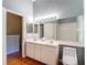 Well-lit bathroom featuring a double sink vanity, large mirror, and view into a bedroom at 12464 Berkeley Square Dr, Tampa, FL 33626