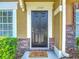 Stylish black front door with brick accents and decorative 'Stay Awhile' welcome mat at 12464 Berkeley Square Dr, Tampa, FL 33626