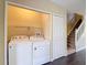 Bright laundry area with full-size, side-by-side washer and dryer in an open closet near the home's stairs at 12464 Berkeley Square Dr, Tampa, FL 33626
