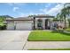 Charming home with a three-car garage, stone accents, lush landscaping, and well-manicured lawn at 12918 Tar Flower Dr., Tampa, FL 33626