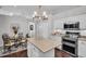 Well-lit kitchen features stainless steel appliances, granite countertops, white cabinets, and an island with a modern chandelier at 12918 Tar Flower Dr., Tampa, FL 33626