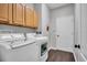Laundry room featuring wood floors, updated machines, and overhead cabinets at 12918 Tar Flower Dr., Tampa, FL 33626