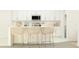 Bright kitchen features modern white cabinets, stainless appliances, and counter seating with rattan chairs at 13118 Empress Jewel Trl, Parrish, FL 34219