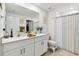Bathroom with double sinks, white cabinets, a large mirror, and shower-tub combo with stylish shower curtain at 13235 Palmerston Rd, Riverview, FL 33579