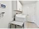 Functional laundry room with white cabinets, washer, dryer, and a wall-mounted smart panel at 13235 Palmerston Rd, Riverview, FL 33579