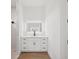 Bathroom features a white vanity with modern fixtures and an illuminated mirror, as well as wood floors at 15218 Appleton Blvd, Port Charlotte, FL 33981
