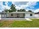 A view of the rear exterior featuring a screened-in lanai and a well-maintained lawn at 17824 Morninghigh Dr, Lutz, FL 33549
