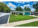 Charming single-story home with a green lawn, a well-kept garden, and a vibrant turquoise garage door at 17824 Morninghigh Dr, Lutz, FL 33549
