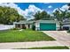 Charming single-story home with a green lawn, a well-kept garden, and a vibrant turquoise garage door at 17824 Morninghigh Dr, Lutz, FL 33549