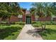 Inviting front entrance with a well-maintained lawn and lush tropical landscaping at 214 Caryl Way, Oldsmar, FL 34677