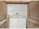 A compact laundry room with a white washer and dryer, wooden folding ladder, and ventilated shelving at 214 Caryl Way, Oldsmar, FL 34677