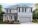 Inviting two-story home featuring a gray exterior, complemented by a well-manicured lawn and lush landscaping at 2328 Stratten Dr, Zephyrhills, FL 33541