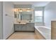 Bathroom with double sink vanity, soaking tub under window and neutral tiling at 3633 Springville Dr, Valrico, FL 33596