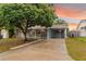 Charming single-story home featuring a covered carport, lush tree, and neutral-colored exterior paint at 4318 Mesa Dr, New Port Richey, FL 34653
