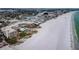 Stunning aerial view showcasing the beach, condo building with pool, and surrounding waterways at 4450 Gulf Blvd # 110, St Pete Beach, FL 33706