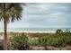 Panoramic view of the beach and ocean with lush vegetation in the foreground at 4450 Gulf Blvd # 110, St Pete Beach, FL 33706