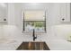 Modern kitchen sink with a window view of the pool, white subway tile, and updated cabinetry at 4522 S Hale Ave, Tampa, FL 33611