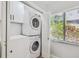 Modern laundry area with stacked washer and dryer, white cabinetry, and natural light from the window at 4522 S Hale Ave, Tampa, FL 33611