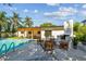 Backyard with a sparkling pool, spa, covered patio with a dining area, outdoor fireplace, and tropical foliage at 4522 S Hale Ave, Tampa, FL 33611