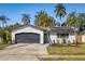 Charming single-story home showcasing a brick facade, dark garage door, and lush landscaping with mature palm trees at 6000 Denver Ne St, St Petersburg, FL 33703