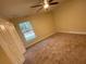 Comfortable bedroom features plush carpeting, a ceiling fan, and a window offering natural light at 6153 La Pine Rd, Brooksville, FL 34602