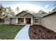 Inviting single-story home with a red front door, manicured landscaping, and a welcoming walkway at 6153 La Pine Rd, Brooksville, FL 34602