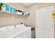 Laundry room with a white washer and dryer and overhead shelving at 7017 Gomez Rocks Ct, Sun City Center, FL 33573