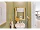Stylish powder room with a pedestal sink, a framed mirror, and olive green paint at 7017 Gomez Rocks Ct, Sun City Center, FL 33573