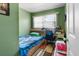 Small bedroom features a single bed, desk, and window with natural light and neutral green paint at 7676 18Th St N, St Petersburg, FL 33702