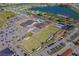 Aerial view of community clubhouse complex featuring a pool, lawn bowling greens, parking, and a nearby lake at 913 Augusta Dr, Sun City Center, FL 33573