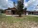 Cozy single-story house featuring brick accents and a covered entrance, surrounded by a green lawn and trees at 9218 N 52Nd St, Tampa, FL 33617