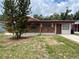 Single-story brick house featuring a welcoming front porch and a mature tree in the yard at 9218 N 52Nd St, Tampa, FL 33617