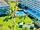 Aerial view of a community featuring a pool, shuffleboard, and manicured lawns with palm trees at 100 Bluff View Dr # 114C, Belleair Bluffs, FL 33770