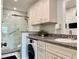 Modern bathroom with a glass-enclosed shower, granite countertops, and a convenient washer-dryer combination at 100 Bluff View Dr # 114C, Belleair Bluffs, FL 33770