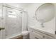 Bathroom with marble tiled shower, brushed nickel fixtures, round mirror, and white vanity at 10219 Huntley St, New Port Richey, FL 34654