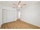 Bedroom features wood-look floors, a ceiling fan, closet, white trim, and door at 10219 Huntley St, New Port Richey, FL 34654