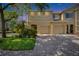 Charming townhome featuring a well-manicured lawn, mature trees, and a paver driveway leading to attached garages at 10606 Shady Falls Ct, Riverview, FL 33578