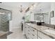 Bathroom vanity with granite countertops, stylish light fixtures, decorative mirror, and glass shower at 10880 Cory Lake Dr, Tampa, FL 33647