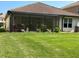 Rear exterior of a home with a screened lanai, complemented by a well-maintained lawn and landscaping at 10880 Cory Lake Dr, Tampa, FL 33647